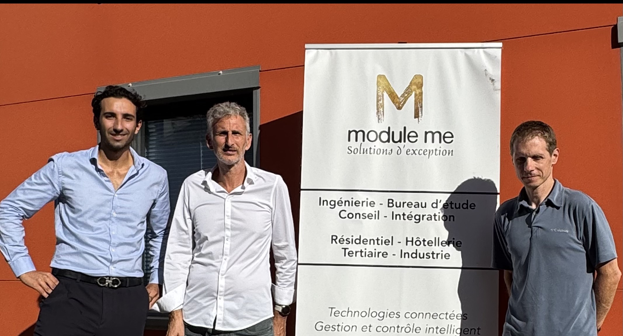 L'équipe module me devant l'enseigne de l'entreprise, sur site.